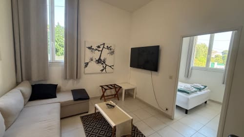 Séjour moderne à la Résidence Kimi à Cannes avec canapé, télévision, baies vitrées sur jardin et carrelage