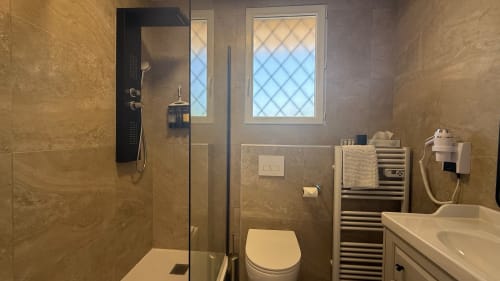 Salle de bain moderne de la Suite Familiale Kimi Résidence, Cannes avec douche à effet pluie, sèche-serviettes chauffant et finitions en marbre