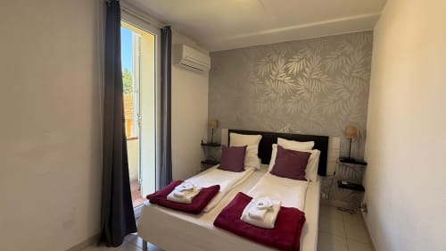 Chambre suite familiale à Kimi Résidence Cannes avec lits jumeaux, accents bordeaux, vue jardin et accès balcon privé