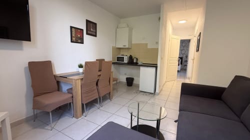 Séjour de la Suite Familiale à la Kimi Résidence à Cannes avec table à manger, canapé, kitchenette et télévision