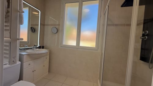 Salle de bains moderne de la suite familiale Kimi Résidence à Cannes avec lavabo, douche et vue sur jardin