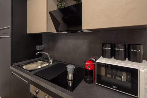 Modern kitchenette in Superior Suite at Taormina apartment with black induction cooktop, stainless sink, and coffee maker