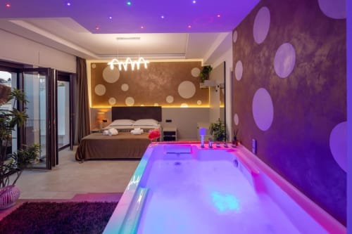 Modern bedroom suite in Taormina with neon-lit amenities, illuminated pool table, and sea views