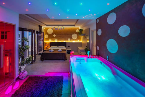 Modern luxury suite in Taormina with neon-lit pool, hot tub, and bedroom with sea views