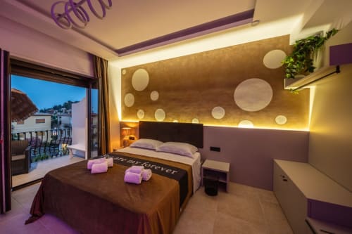 Luxury Superior Suite apartment in Taormina with purple accents, modern bed, golden accent wall, balcony with sea view