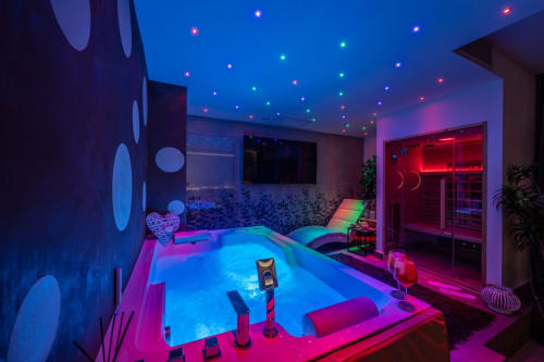Modern luxury spa apartment in Taormina with neon-lit pool, pink and blue ambient lighting, sauna, and contemporary design