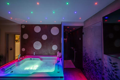 Modern luxury bathroom suite in Taormina with neon-lit hot tub, rainfall shower, and ambient colored ceiling lights