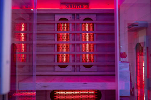 Modern sauna room with red infrared lights and wooden benches at Suite Apartment Taormina luxury BnB in Taormina, Italy