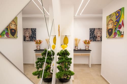 Modern apartment entryway with mirror, topiary plants, colorful pop art portraits, and white desks at Suite Apartment