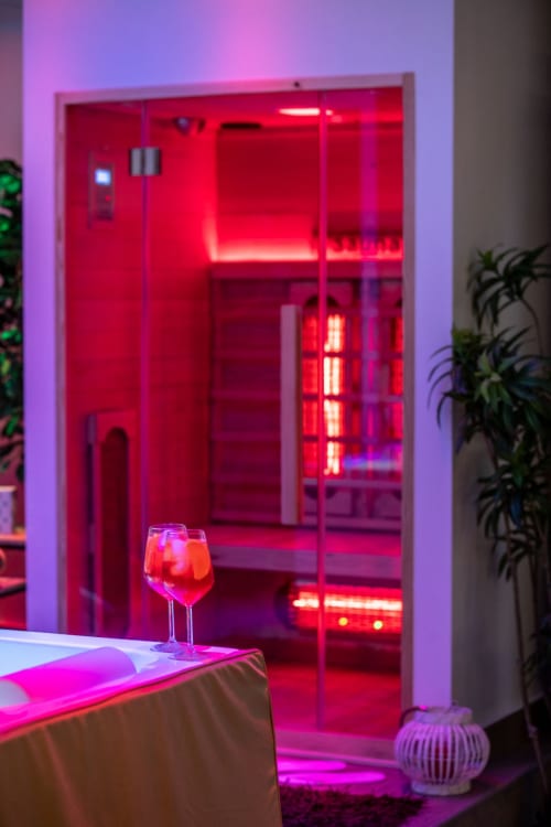 Modern red neon-lit infrared sauna cabin with glass doors in Suite Apartment Taormina, featuring geometric decor and ambient