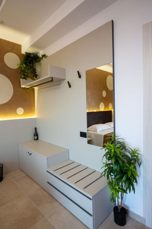 Modern Superior Suite bathroom at Taormina apartment with vessel sink, mirror, heated towel rack, plants, and bedroom view