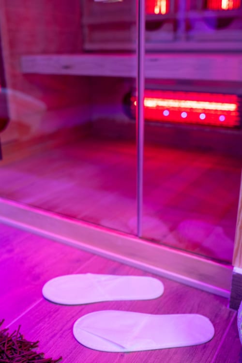 Modern bathroom with neon pink and purple lighting, white oval bath mats, and red LED lights in Suite Apartment Taormina