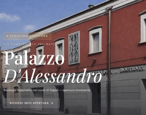 Red palazzo facade with ornate white trim on Via Poggioreale in Naples, announcing Palazzo D'Alessandro boutique hospitality