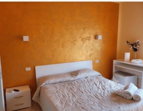 Camera luminosa arancione all'Il Rifugio D'Amare di Agropoli con letto bianco, comodino e arredi moderni