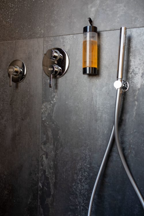 Modern bathroom fixtures in Suite Apartment Taormina, showing chrome shower controls and argan oil dispenser on gray tile