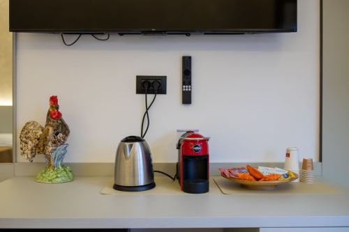 Kitchen counter in Taormina B&B suite with kettle, coffee machine, decorative rooster, and snacks