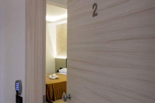 Doorway to Superior Matrimoniale room at Suite Apartment Taormina, showing bed with gold bedding and modern minimalist