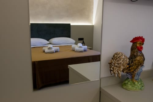 Modern bedroom at Suite Apartment Taormina with double bed, white pillows, rolled towels, and decorative rooster figurine