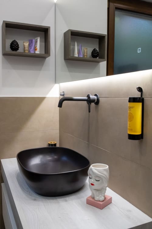 Modern bathroom sink with black bowl vessel, white head sculpture, and wall-mounted faucet at Suite Apartment Taormina