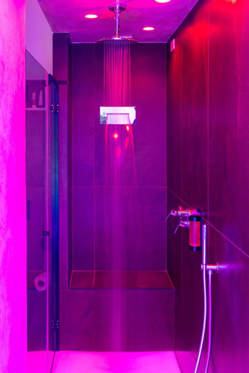 Modern bathroom shower with vibrant pink neon lighting at Suite Apartment Taormina, featuring glass enclosure and