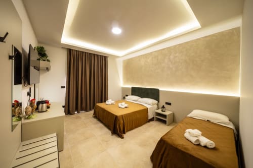Modern double bedroom at Suite Apartment Taormina with dual beds, amber linens, LED ceiling lights, and contemporary