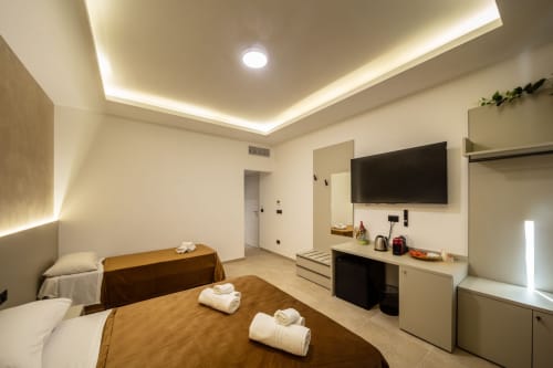 Modern Superior suite bedroom at Taormina B&B with flat-screen TV, ambient lighting, double bed with rolled towels,