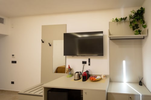 Modern kitchenette in Suite Apartment Taormina with flat-screen TV, appliances, and potted plant on shelf