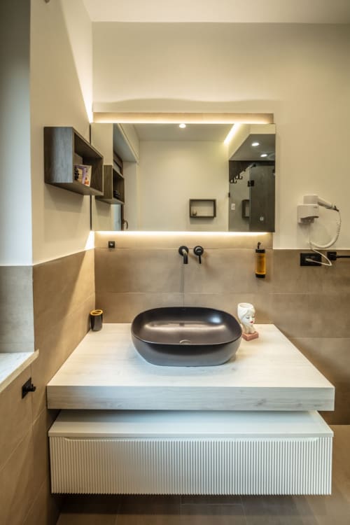 Modern bathroom with black oval sink and illuminated mirror at Suite Apartment Taormina, Sicilian luxury accommodation