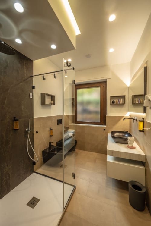Modern luxury bathroom in Taormina suite with walk-in shower, marble countertop vanity, and garden views from window
