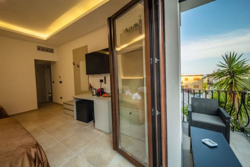 Modern suite bedroom with balcony, flat-screen TV, and garden view at Suite Apartment Taormina, Sicily