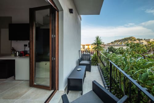 Balcony terrace at Suite Apartment Taormina with garden views, outdoor seating, and Sicilian hillside backdrop