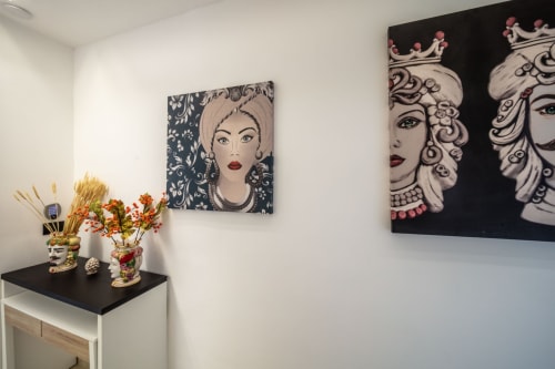Modern hotel room at Suite Apartment Taormina featuring decorative portrait artwork, floral arrangements, and contemporary