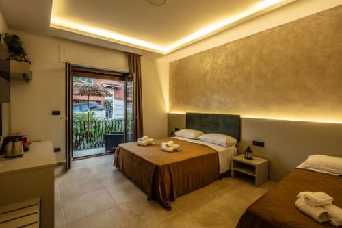 Luxurious bedroom suite in Taormina with king bed, ambient lighting, marble floors, and garden view balcony
