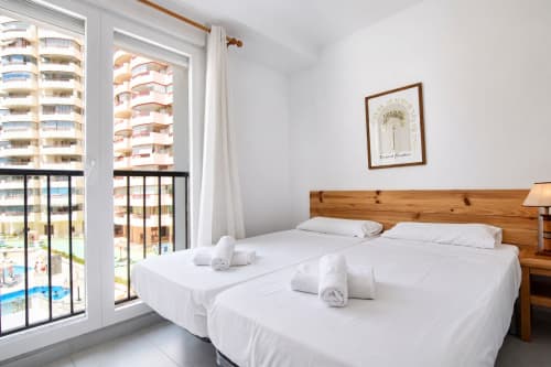 Dormitorio luminoso en Riurau Home Calpe con camas gemelas, balcón con vistas al mar, cabecero de madera y comodidades modernas