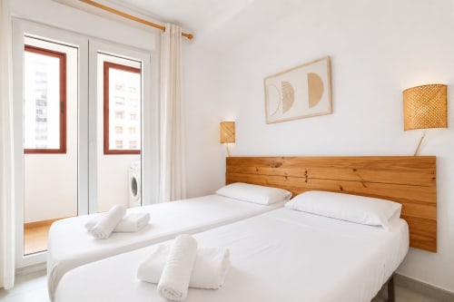 Luminoso dormitorio doble en apartamento Riurau Home Calpe con cabecero de madera, balcón con vistas al mar y comodidades modernas