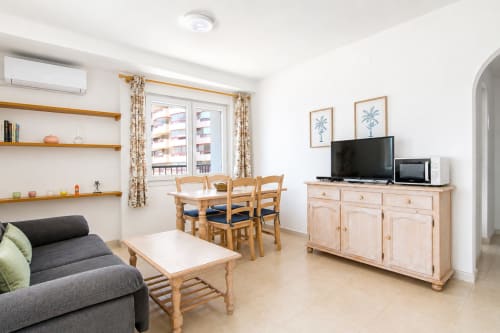 Luminoso salón de apartamento en Calpe con vistas al mar, muebles de madera, TV de pantalla plana, sofá y comedor