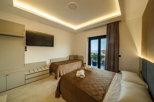 Modern superior suite bedroom in Taormina with double beds, sea view balcony, flat-screen TV, and marble flooring
