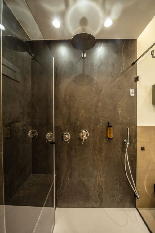 Modern walk-in shower with dark marble tiles and rainfall showerhead at Suite Apartment Taormina, Sicily