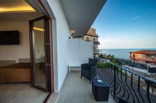 Superior balcony suite in Taormina with sea view, black outdoor furniture, and Ionian Sea vista overlooking Mediterranean