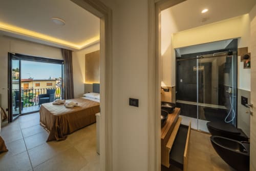 Luxury suite bathroom and bedroom in Taormina with sea view balcony, marble floors, and modern amenities