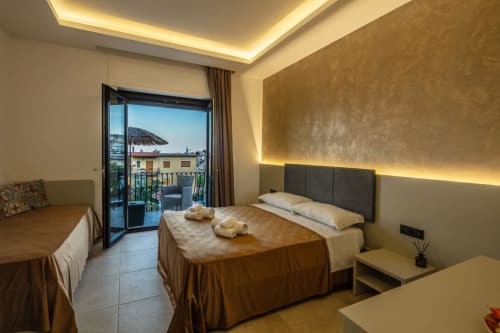 Luxury bedroom suite in Taormina with sea view balcony, double bed, and coastal mountain landscape
