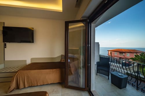 Taormina Superior bedroom with sea view balcony, double bed, flat-screen TV, and Ionian Sea vista