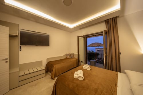 Luxury superior double bedroom in Taormina with sea view balcony, marble floors, flat-screen TV, and mountain vistas
