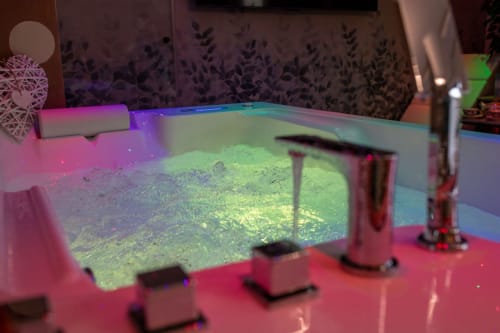 Illuminated Jacuzzi hot tub with vibrant colored LED lights in Suite Apartment Taormina luxury suite