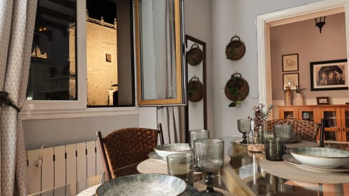 Elegante comedor del hotel Mirador Medieval en Cáceres con mesa puesta, espejos y cestas tejidas decorativas en las paredes.