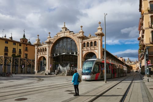 Tranvía moderno pasando por la histórica estación Mercado Central en el centro de Zaragoza, cerca del Hostal Zaragoza Centro