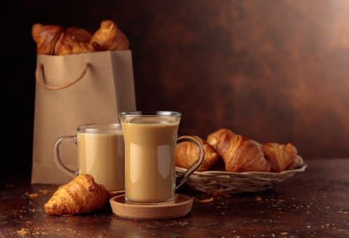 Petit-déjeuner Ô de Mer avec café, croissants dans un panier et un sac en papier, lumière chaleureuse