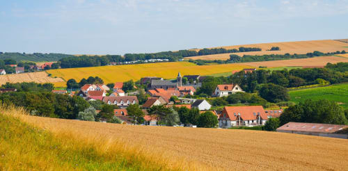 Village rural français niché dans les champs agricoles vallonnés près de Sangatte, aux maisons aux toits rouges et clocher caractéristique