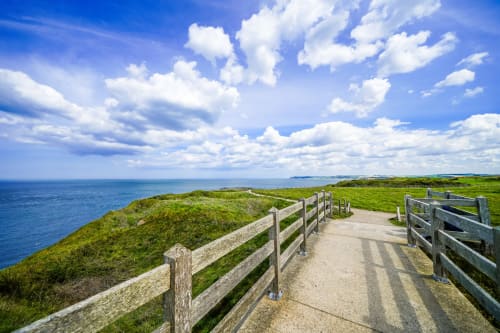 Passerelle en bois dominant la mer bleue et les falaises verdoyantes à Ô de Mer, Sangatte, France