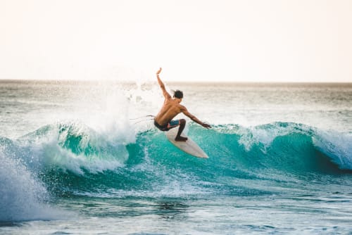 Surfer riding turquoise wave near Ô de Mer hotel in Sangatte, France